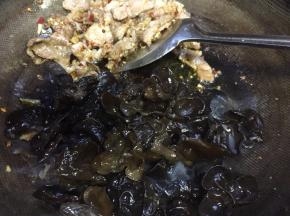 把肉片推至一边，倒入黑木耳，让黑木耳充分吸足油料