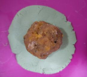 取一份糯米团按扁，放入一份蛋黄肉松馅。