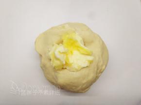 除黄油和黑芝麻外，将面团中的其它原材料按照底层液体，中层粉类，上层糖、盐和酵母的顺序放入面包桶中，启动一个揉面程序，揉至能拉出厚膜后加入黄油，继续一个揉面程序，揉至扩展阶段。