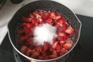 再把草莓丁倒入不粘锅中，加入剩下的白糖，开中小火熬制，熬制过程中再加入15毫升的新鲜柠檬汁