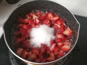 再把草莓丁倒入不粘锅中，加入剩下的白糖，开中小火熬制，熬制过程中再加入15毫升的新鲜柠檬汁