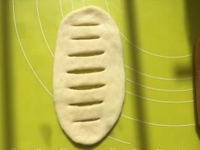 将擀好的面片翻个面，将光滑的一面放在底下，之后用刀在中间划开几道，一定要划透