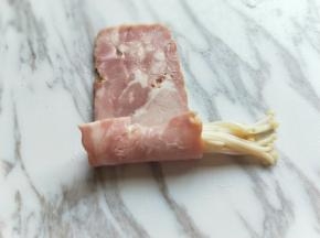 取一片培根，放上金针菇，卷起来。