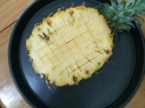 菠萝冲洗干净表皮，然后在三分之一处切开。用水果刀打十字。