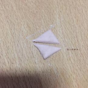 小猪的身体做好后，来做耳朵的部分，将面团擀开，用刮刀切出5份正方形，每个正方形如图，对角切开