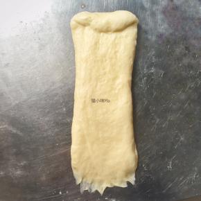 醒发好的面团擀成长蛇状，从上往下卷起