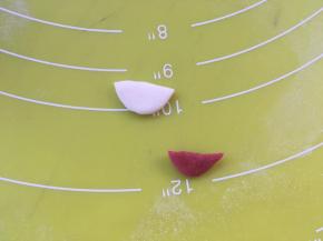 取一份白色面团擀成圆片，用剪刀剪成嘴巴的形状，再取一份红色面团擀成圆片，剪成比白色面团小一点的嘴巴形状