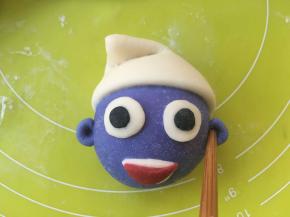 取两小块蓝色面团，点一点点水，黏在两侧做耳朵，再用筷子在中间点一下，形成耳蜗，做好后的蓝精灵松弛半个小时左右，让面团二次发酵，面团膨胀变大，按压有弹性即可