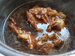 完成后从压力锅中倒入一个深盆中，这时候可以看到肉表层和牛筋都上色了。把肉继续浸泡在汤汁中放凉。