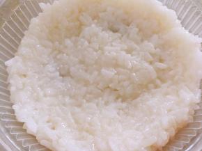 挖一勺糯米饭放进碗里，中间低，四周高一点