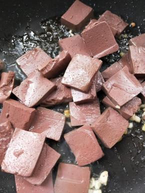 起油锅，放姜葱蒜煸炒，倒入猪血。