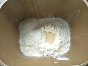 倒入面粉，尽量全部盖住牛奶液，把白糖放在面包机的一角，面粉中间挖个眼，倒入酵母，让酵母不会直接与糖和盐接触