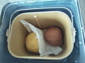 把两种颜色的面团放入面包桶，中间用一张油纸隔开，以防粘连，再按启动键，进行基础发酵