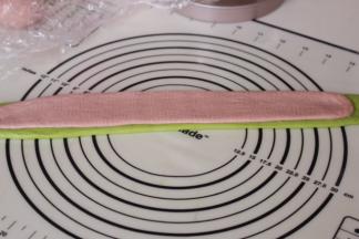 松弛好的面团排气，擀成长舌形，紫色稍比绿色短