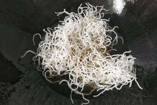 然后取适量粉丝放入锅中，粉丝入油便迅速开花