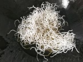 然后取适量粉丝放入锅中，粉丝入油便迅速开花