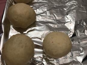 收口部朝下放入铺好锡纸的烤盘上，每一个间隔一定的空隙（大约是面包坯的一半）放入烤箱内发酵至两到三倍大