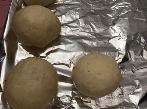 收口部朝下放入铺好锡纸的烤盘上，每一个间隔一定的空隙（大约是面包坯的一半）放入烤箱内发酵至两到三倍大
