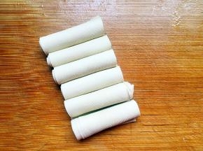 将豆腐皮切分，一个个卷起来。