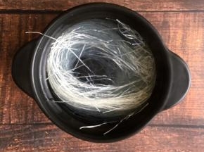 准备一个煲，里放入粉丝，倒入开水浸泡