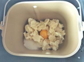 称出主面团材料，把中种面团撕成小块放入面包桶，把糖和盐对角放，倒入鸡蛋，然后倒入50克面粉，倒入一克酵母，黄油先不放，然后开启揉面程序，10分钟