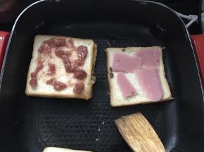 将草莓酱，火腿片，鸡蛋夹入四层白吐司中，压紧。