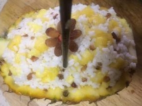 再取几颗葡萄干做装饰，用筷子给菠萝饭插数个小孔以便上汽