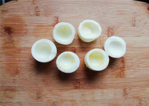 把鸡蛋对半切开，蛋黄挖掉跟主料一起，蛋白杯底部切平，能站立即可