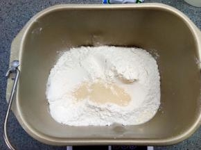 先放液体，再放面粉，糖和盐分别放在面包机桶对角，面粉上挖坑埋入酵母，启动程序揉面，揉至初步扩展，放入软化的黄油，继续揉至完全扩展状态，然后发酵。