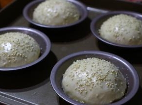 发酵好的面包表面刷上一层牛奶，撒上少许白芝麻。