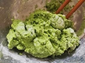 把白糖放进糯米粉里面，加油，用筷子搅拌一下，倒入青汁，用筷子搅拌成絮，再用刮刀翻压均匀