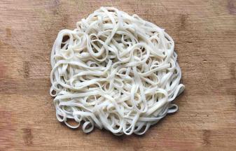 把沥干水分的面条放在砧板上，如图这样叠一起，等待面条变干