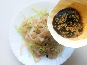 将控干盐水的海蜇丝放入盘中，倒入酱汁