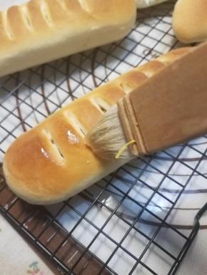 出炉后的面包移至晾架上，温热时用毛刷沾上融化的黄油，刷在表面装饰。