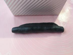 卷起，如图留1cm的边不卷，将卷好的黑色面团放入吐司盒中间位置，1cm凸出的边贴着刚才已摆入吐司盒的蓝色面团