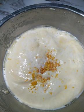 5、倒入牛奶和玉米油的混合液，方法为倒在刮刀上，缓慢的倒入面糊中，再加入橙皮，翻拌均匀。