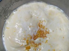 5、倒入牛奶和玉米油的混合液，方法为倒在刮刀上，缓慢的倒入面糊中，再加入橙皮，翻拌均匀。