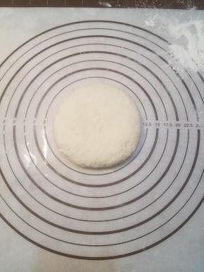 醒好的面团揉压成圆饼状。