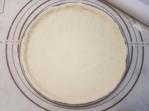 披萨盘涂抹一层黄油，再把面块放置在披萨盘里，整理边缘，使其贴服。