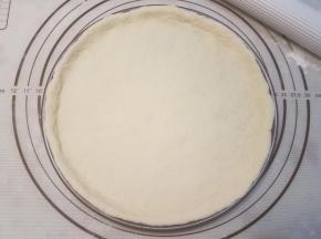 披萨盘涂抹一层黄油，再把面块放置在披萨盘里，整理边缘，使其贴服。