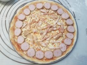 接着铺一层马苏里拉奶酪，摆放脆皮肠片和培根肉。