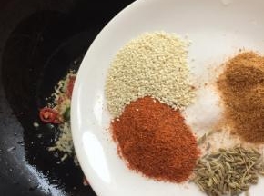 放入辣椒粉，小茴香籽，孜然粉，盐和白芝麻小火煸炒出香味儿。