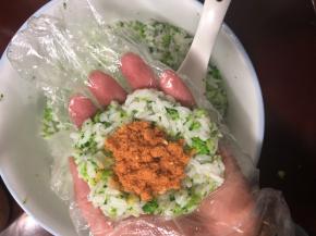 取一团米饭，团成圆形按扁，包上肉松。