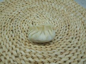 在饺子皮放适量的馅，饺子皮四周沾上水，使皮容易粘合，饺子皮中间先捏一下，两边向中间将饺子皮边缘弄成褶皱状，