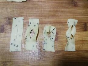 2指宽的长条再切成约5cm长的小段，用刀从中间切一下，然后如图将上部面片从中间的切口穿进去再拉出，2指宽的麻叶整形就做好了