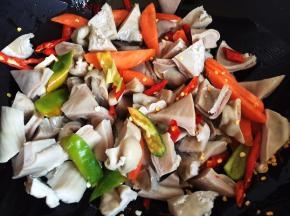 放入猪肚块、胡萝卜片和尖椒块翻炒片刻