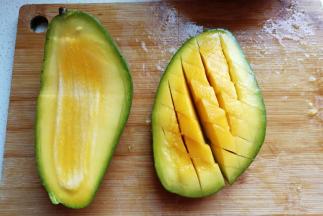 
准备大芒果两个先对半切开，再打上十字斜刀，把芒果向下翻转，然后用刀切下芒果块
