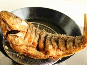 油温再升高一点，把炸熟的鱼再放进去复炸一次，这一步可以使表皮更脆，也能逼出多余的油份。这一步不要炸太久，半分钟即可。扎好的鱼捞出来控一下油，趁热油里再丢几块萝卜炸一下去除鱼腥味。这样油也不会浪费了，可以继续留着炒菜。