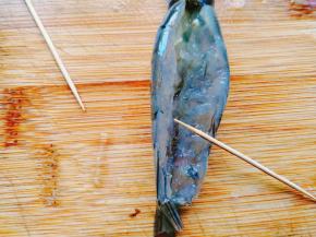 接着，将剪开的虾身部分左右分开、摊开。用牙签将沙肠去掉。把虾用流动的水冲洗干净。