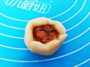 取一份面团压扁，中间挖一点馅料进去，包裹起来